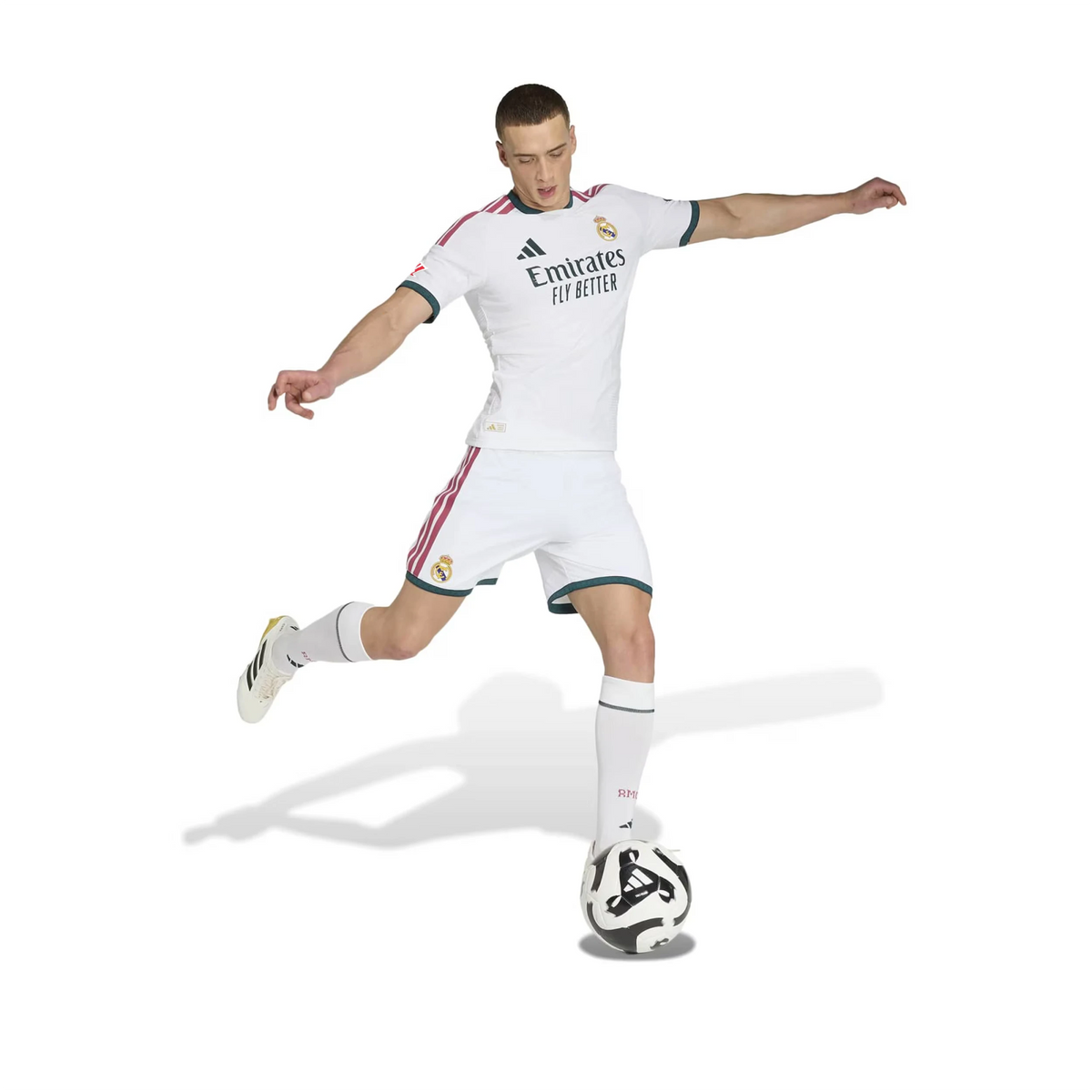 Person wearing a Real Madrid soccer uniform kicking a ball on a white background