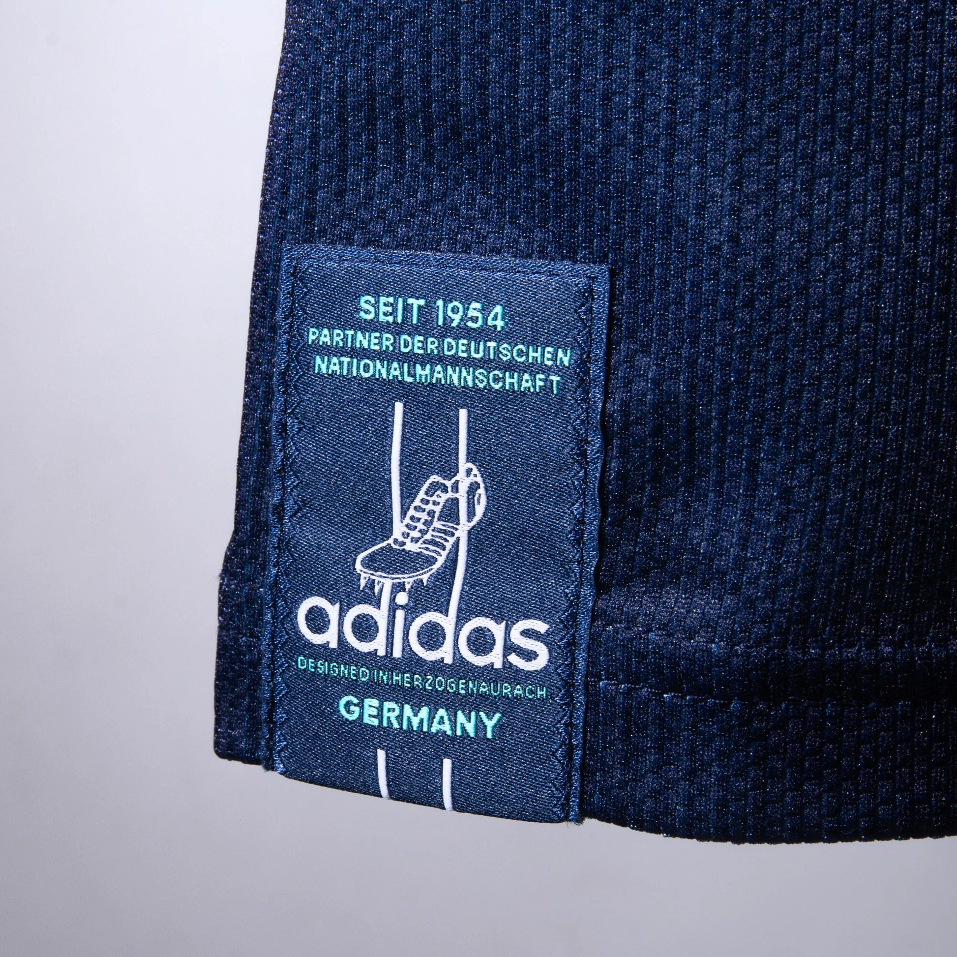 Close-up of Adidas label on a dark blue textured fabric background