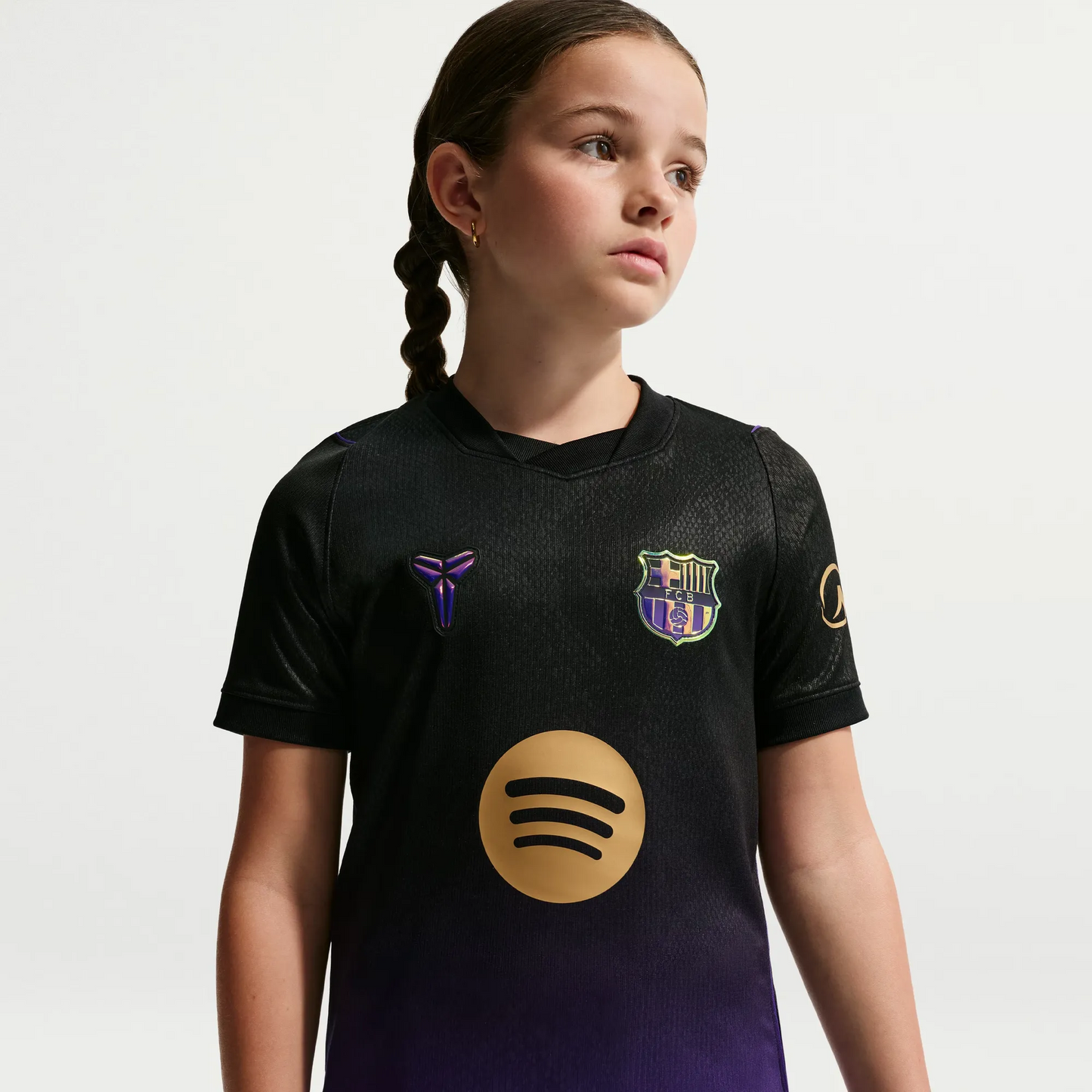 A young girl with braided hair wearing a Barcelona Youth 2026_27 Away Stadium Replica Custom Jersey
