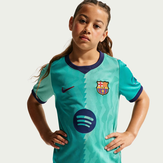 A young girl wearing a turquoise Barcelona 2026-2027 third turquoise stadium replica football shirt