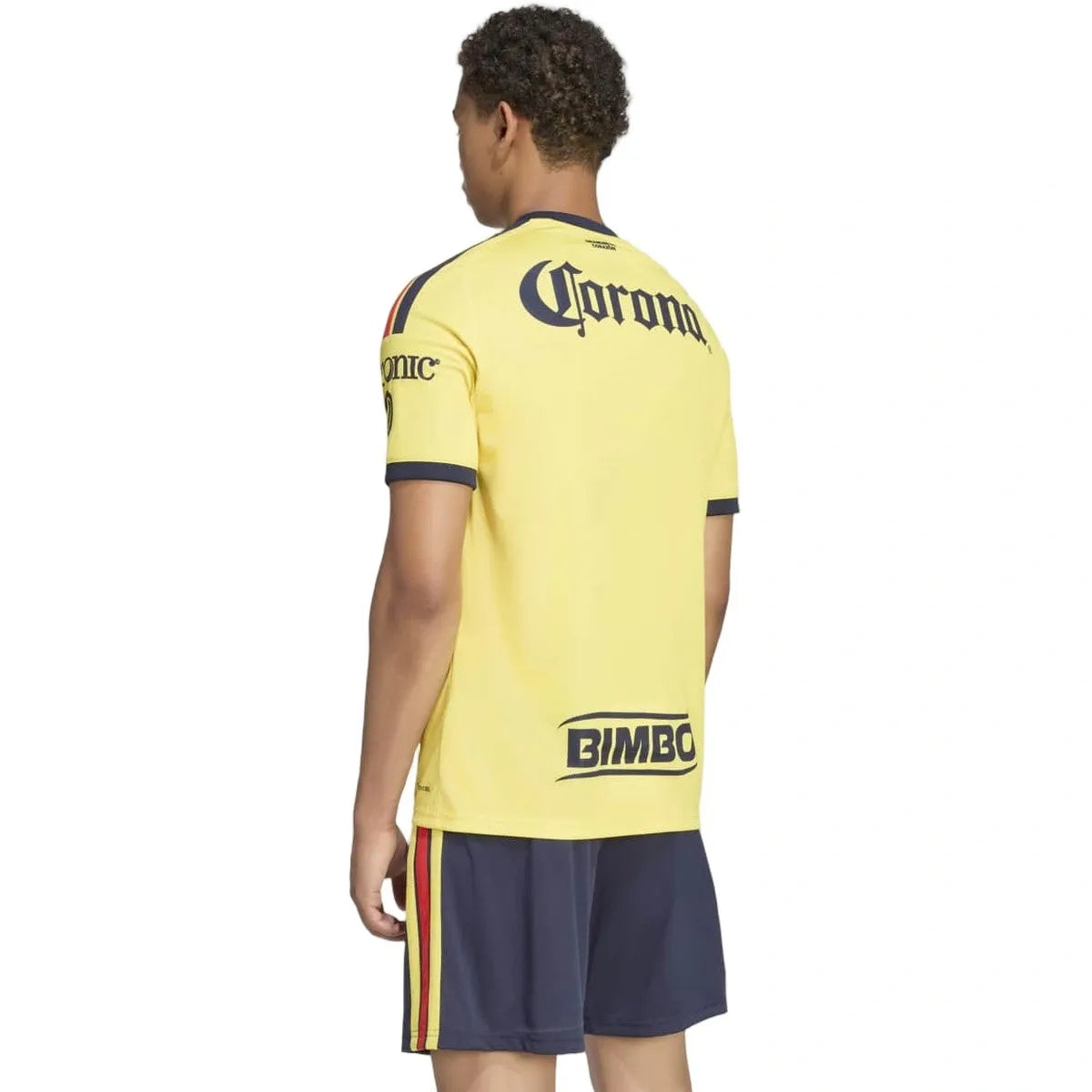 A man shown from the back wearing a yellow short-sleeve soccer jersey with navy blue trim and logos, paired with navy shorts, against a plain white background.