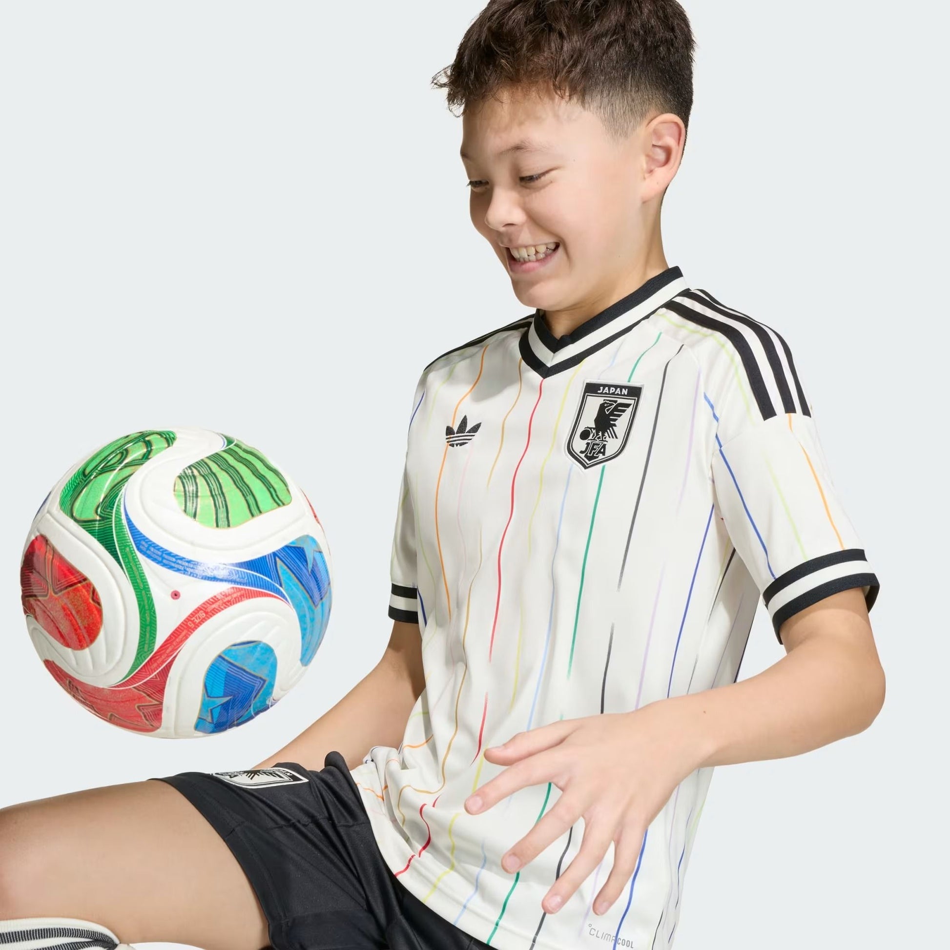 boy wearing a Kids Japan 2026 World Cup away stadium replica jersey with a ball