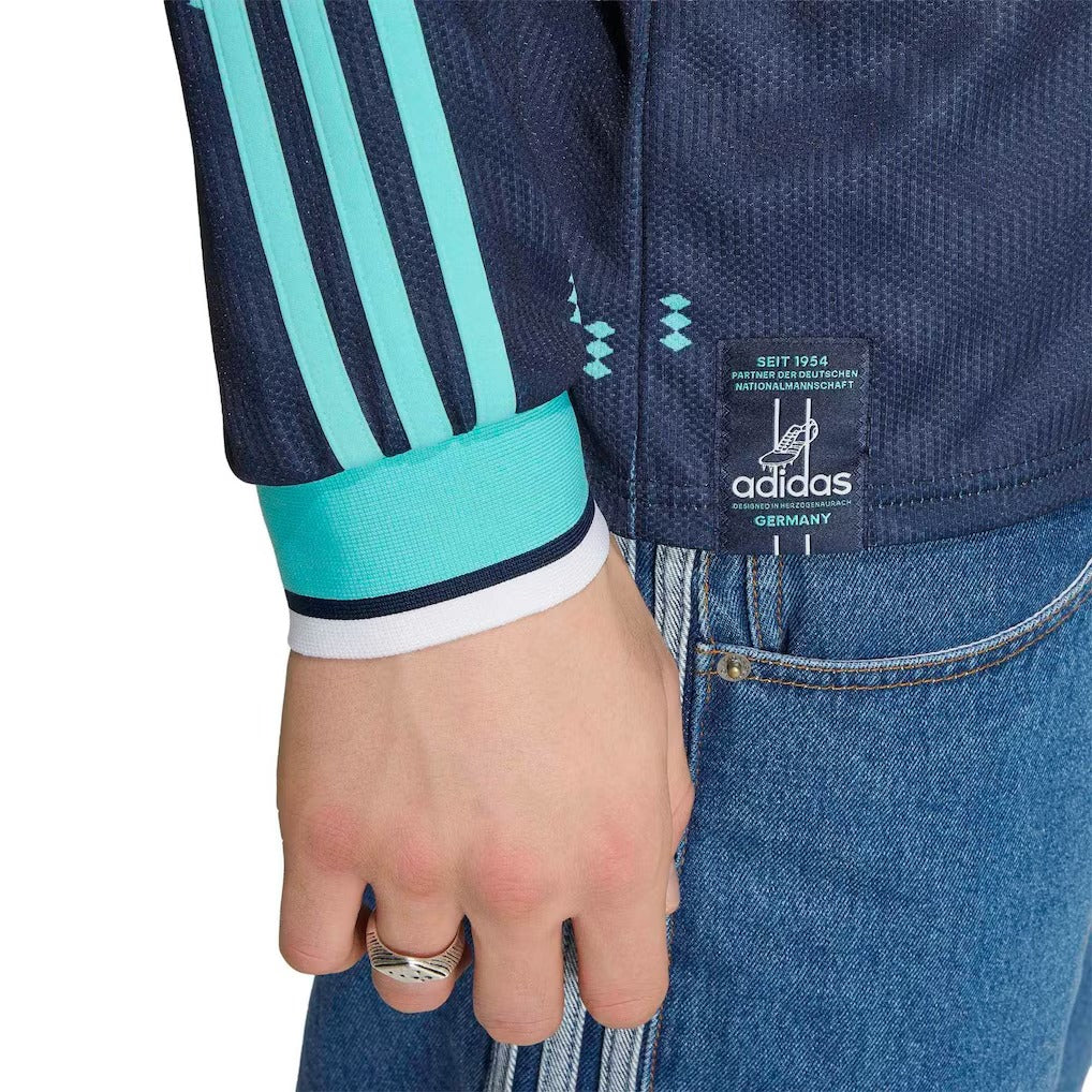 Close-up of a person wearing a blue Adidas jacket with a visible brand label.