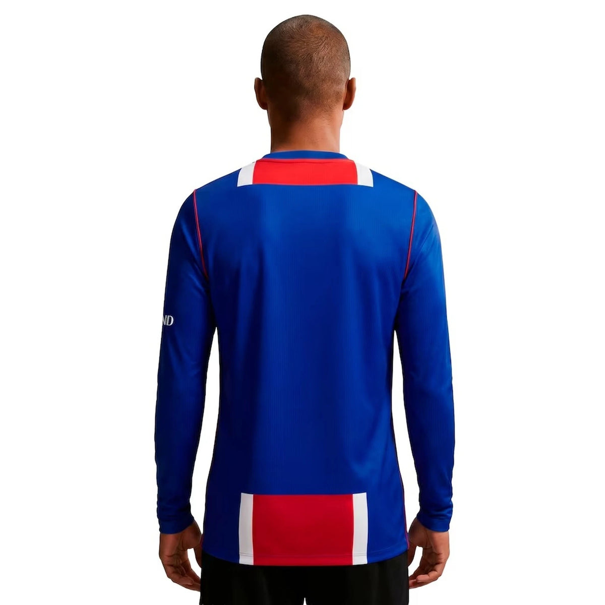 A man viewed from behind wearing a royal blue long-sleeve athletic jersey with red and white block accents on the shoulders and lower back, against a plain white background.