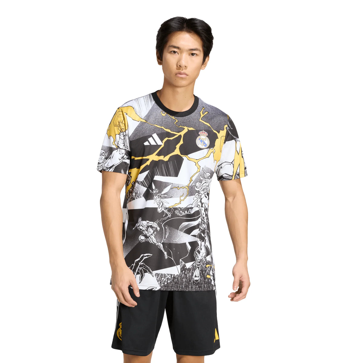 A male model wearing an Adidas Real Madrid soccer jersey with a black, white, and gold abstract graphic print, paired with black shorts, against a plain white background.