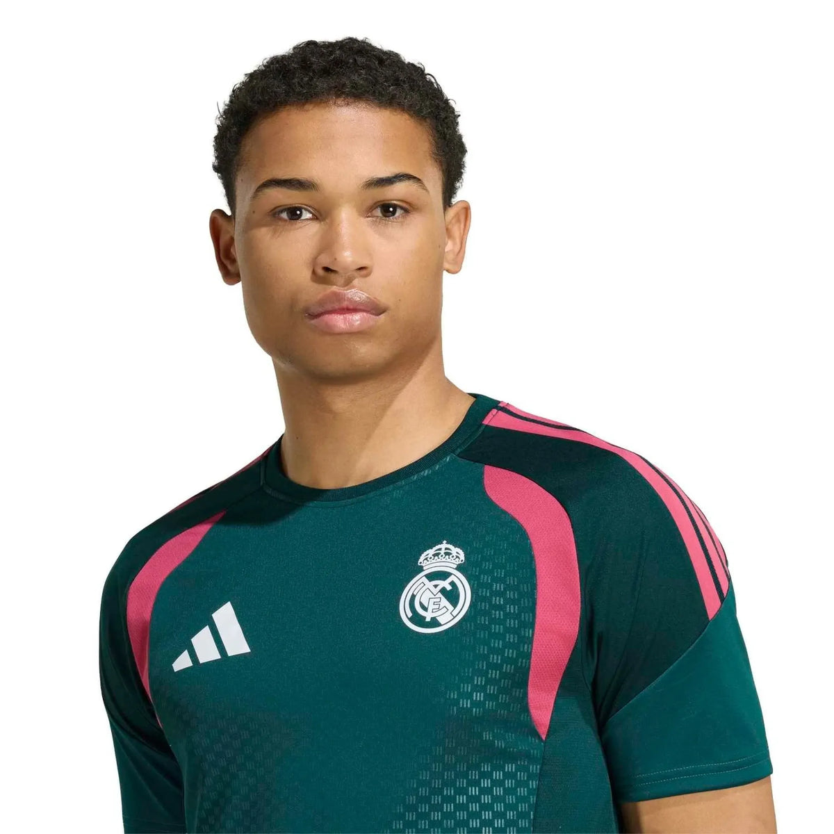 A man wearing a dark green Real Madrid training top with pink shoulder stripes and white Adidas logo, photographed against a solid white background.