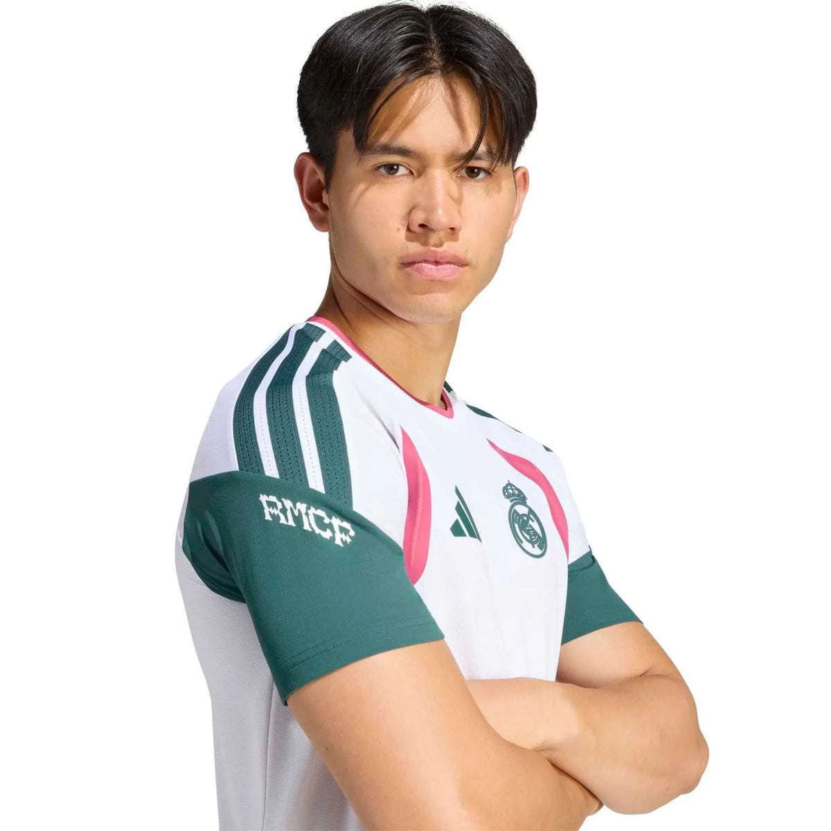 A man wearing a white, green, and pink Real Madrid soccer jersey with the RMCF sponsor logo on the sleeve, photographed against a solid white background.