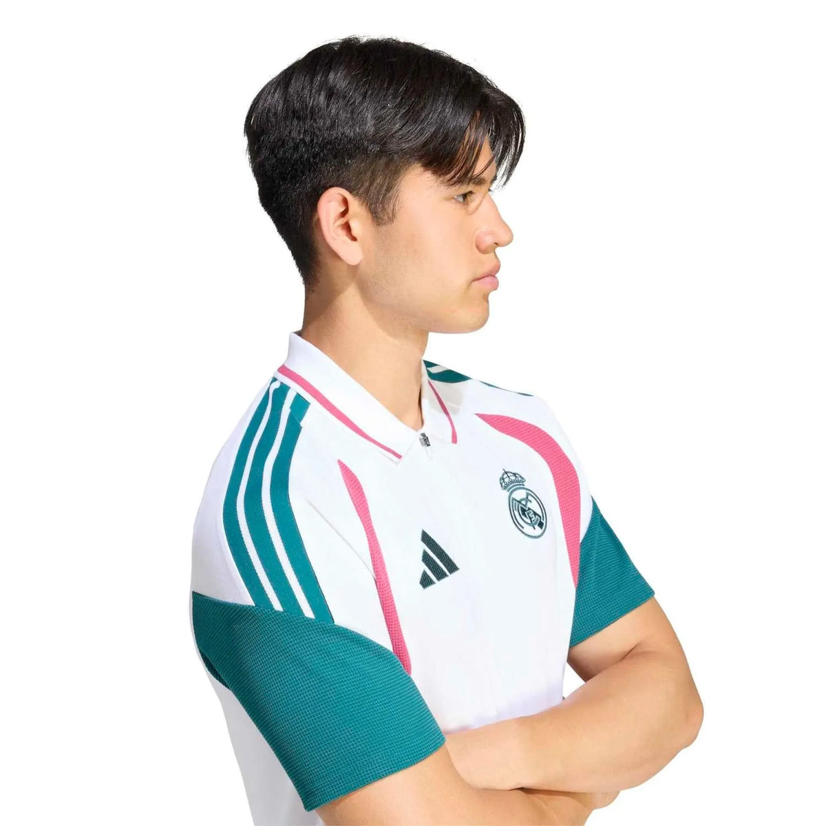 A man wearing a white Real Madrid short-sleeve soccer jersey with teal green and pink accents, shown in a side profile against a white background.