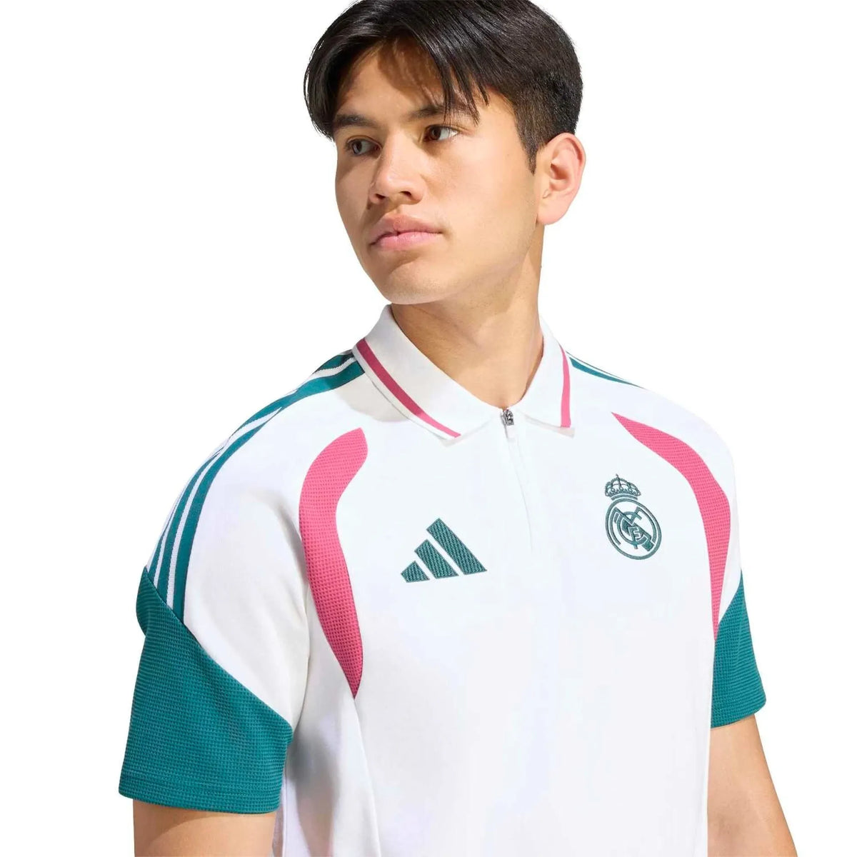 A man wearing a white Real Madrid soccer polo shirt with pink and teal accents, featuring the Adidas logo and Real Madrid crest, set against a plain white background.