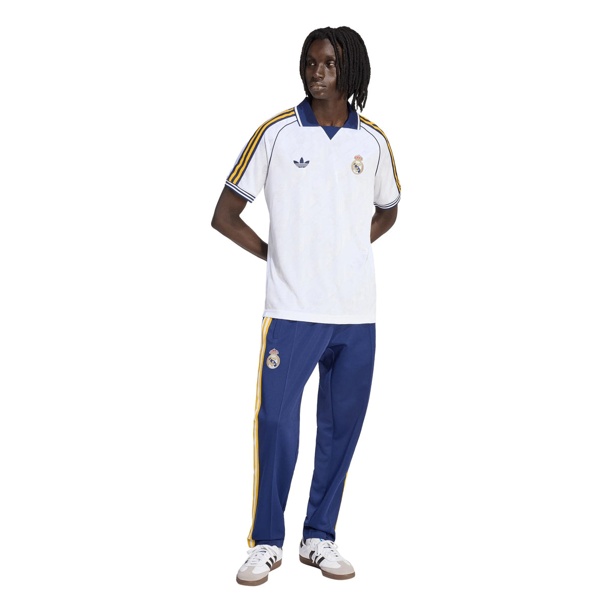 Person wearing a white and blue sports outfit with Adidas and Real Madrid logos on a white background