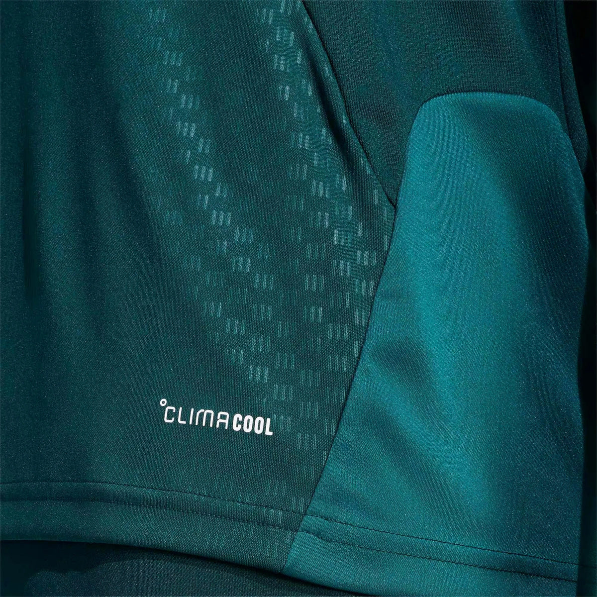 Close-up of a teal athletic garment showing a textured patterned panel and a smooth side pocket, with the white 'clima cool' logo near the lower left.