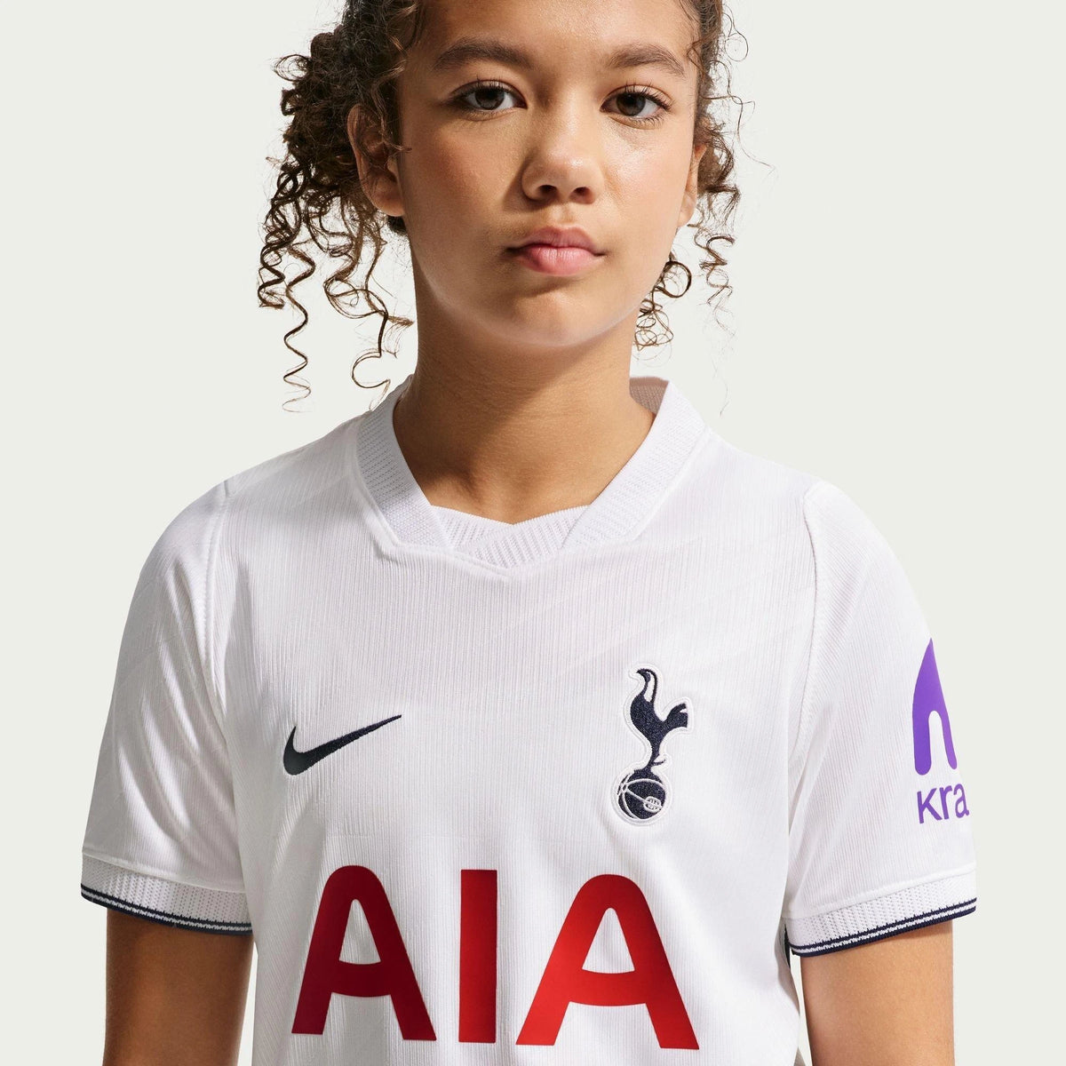 Child wearing a Tottenham Hotspur jersey with Nike and AIA logos on a white background