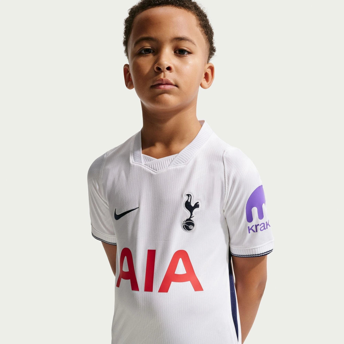 Child wearing a Tottenham Hotspur football jersey with Nike and AIA logos on a white background