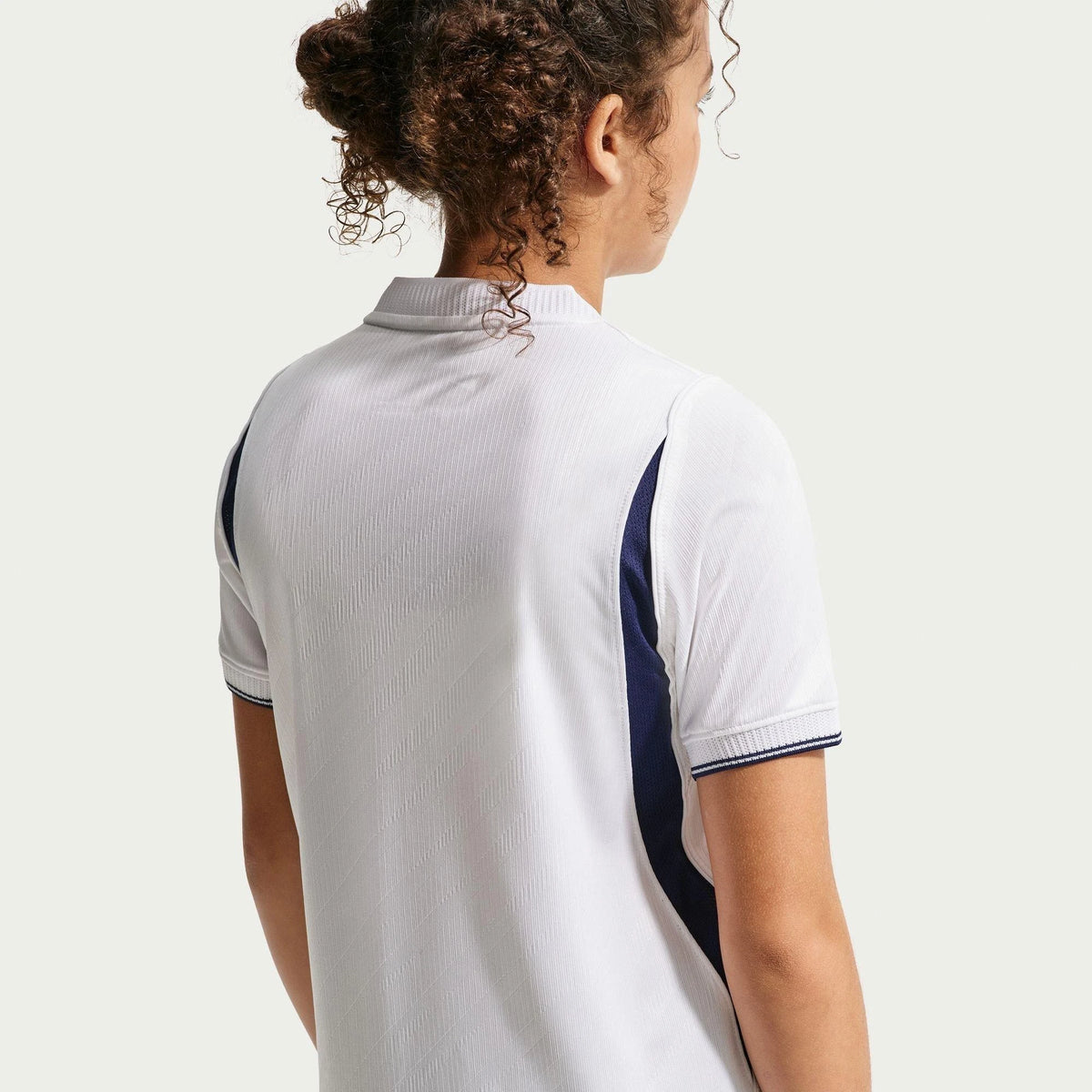 Person wearing a white polo shirt with navy accents on a plain background